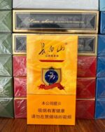 Changbaishan 777 cigarette packaging, single orange pack in front of stacked retail cartons