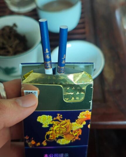 Zhenlong Haiyun Slim cigarette packaging, opened navy pack held with two cigarettes visible