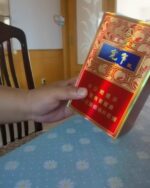 Jiaozi Kuanzhai Wuliang Mid cigarette packaging, front of a red and gold pack held over a table