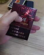 Liqun Sunshine Zun Mid cigarette packaging, front of the red and black pack held in one hand