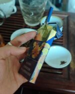 Zhenlong Haiyun Slim cigarette packaging, opened blue pack held in one hand with a cigarette pulled out