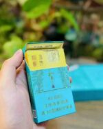 Baisha Heaven Zunpin Slim cigarette packaging, opened blue pack held outdoors to show the inner foil