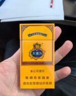 Hand holding a closed cigarette pack.