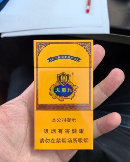 Hand holding a closed cigarette pack.