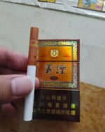 Guiyan Guojiuxiang Slim cigarette packaging, amber and brown pack displayed with a single cigarette
