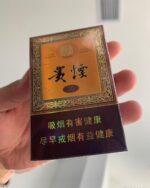 Guiyan Guojiuxiang Slim cigarette packaging, front of the amber and brown pack held in one hand