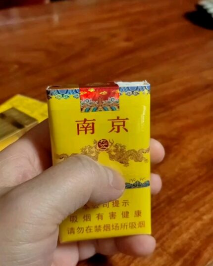 Nanjing Soft 95 Slim cigarette packaging, front of the yellow pack held over a wooden table