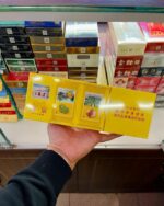 Nanjing Rain-Flower Mid-Slim cigarette packaging, unfolded yellow presentation sleeve held in a tobacco shop