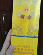 Nanjing 95 Slim cigarette packaging, front of the long yellow pack held in one hand