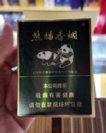 Panda Classic Mid cigarette packaging, front of a dark green panda pack held in a shop