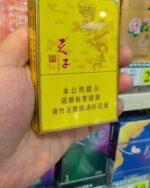 Tianzi Mid-Slim pack held cigarette packaging, front of the yellow pack held in a tobacco shop