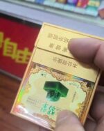 Yuxi Jadeite Slim cigarette packaging, rear panel of the gold pack held in one hand